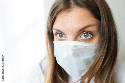 Close up of a female nurse putting on a mask to protect from airborne respiratory diseases such as the flu  coronavirus  ebola  TB  etc copyspace