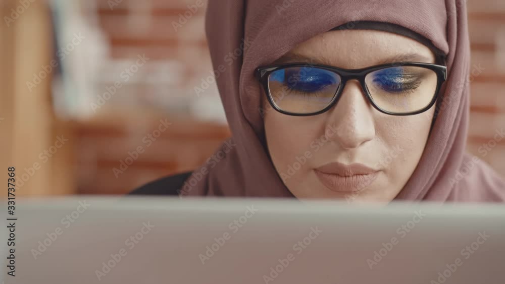 A view from the back of the laptop of a girl in a hijab. Close-up of the eyes of a Muslim woman working at a laptop, view from the laptop cover A view from the back of the laptop of a girl in a hijab. Close-up of the eyes of a Muslim woman working at a laptop, view from the laptop cover