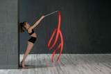 horizontal portrait of a beautiful flexible girl gymnasts on a dark gray background