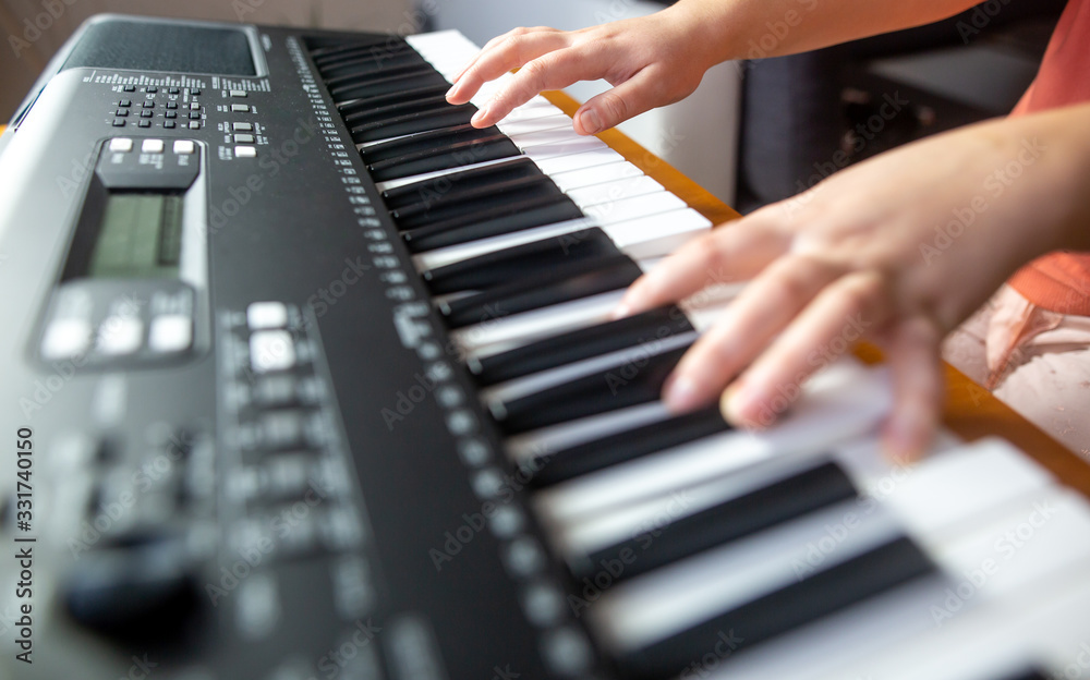 Fototapeta premium Young female beginner teaches itself playing on the electric piano, instrument playing, teachning