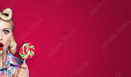 Half face portrait of excited woman with lollipop. Girl pin up with open mouth. Retro fashion and vintage concept. Red color background. Copy space for some text. Wide horizontal banner composition.