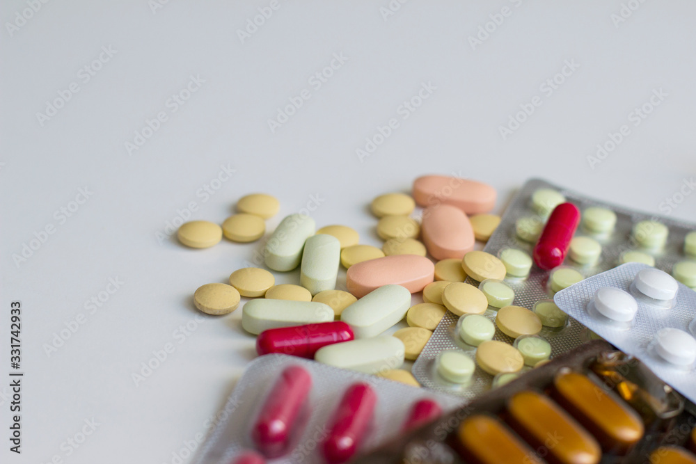 Multi-colored pills and capsules on a white background. Pills in a plastic blister. Healthcare and medicine concept. Multi-colored pills and capsules on a white background. Pills in a plastic blister. Healthcare and medicine concept.
