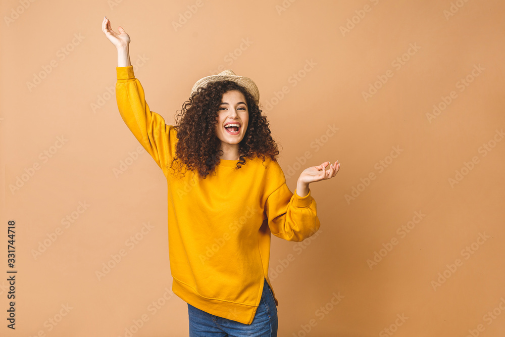 Happy winner. Portrait of cheerful positive girl jumping in the air looking at camera isolated on beige background. Life people energy concept.