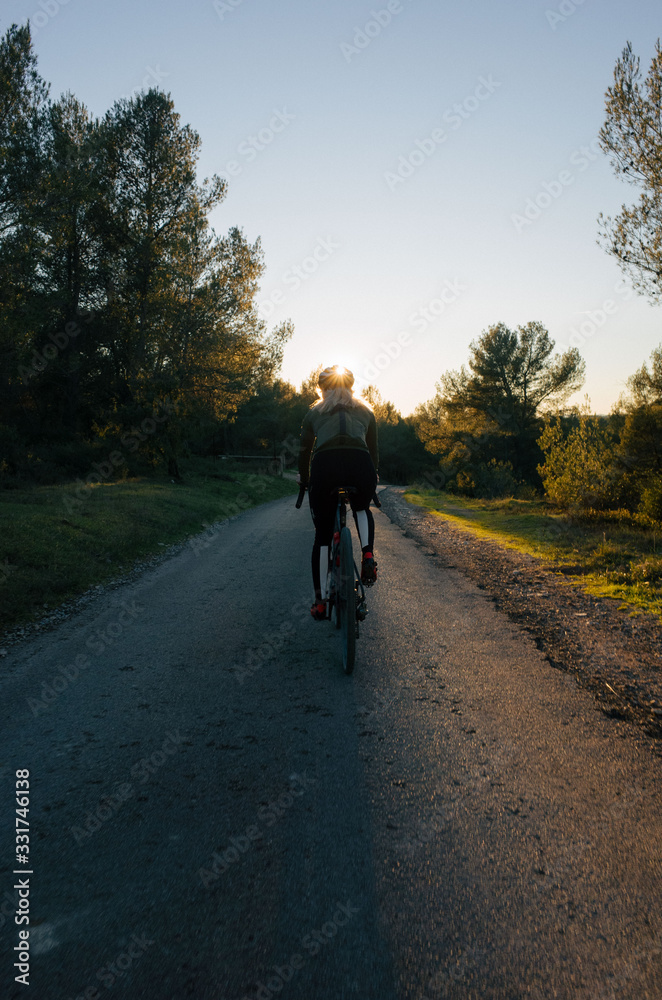 Young female cyclist rides into the sunset