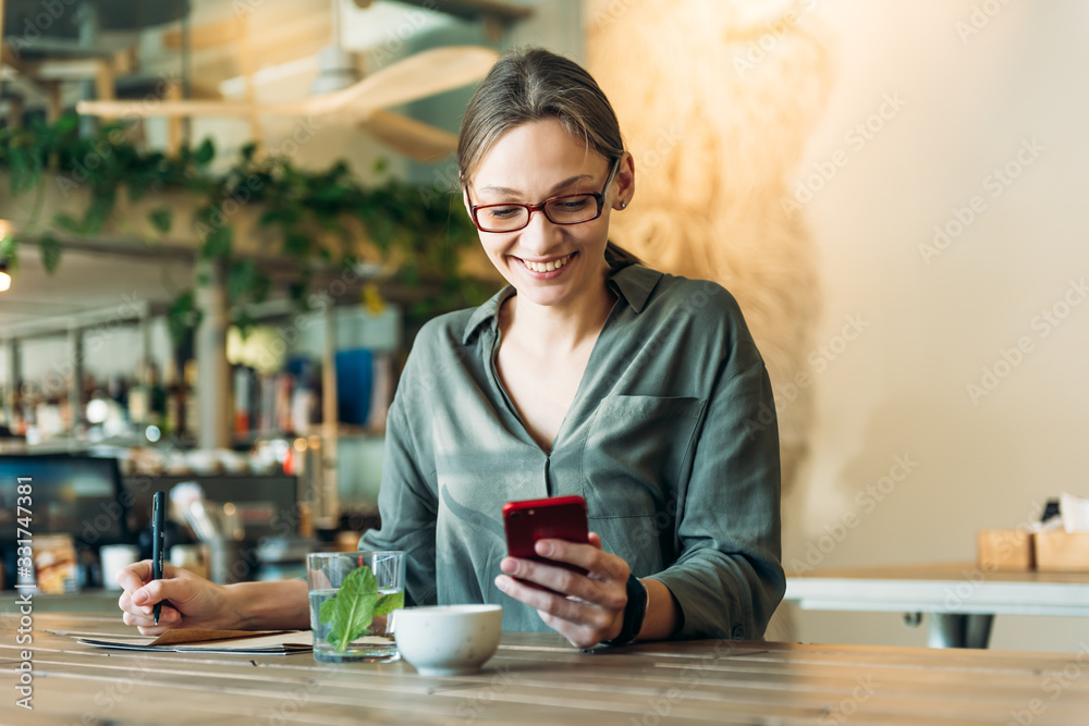 Caucasian businesswoman working at her desk in cafe. Female executive looking away and smiling. Woman working on laptop sitting at cafe. Caucasian businesswoman working at her desk in cafe. Female executive looking away and smiling. Woman working on laptop sitting at cafe.