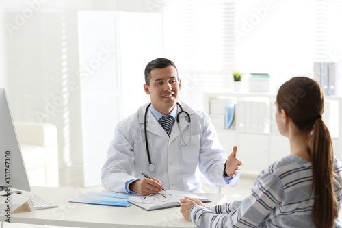 Doctor consulting patient at desk in clinic