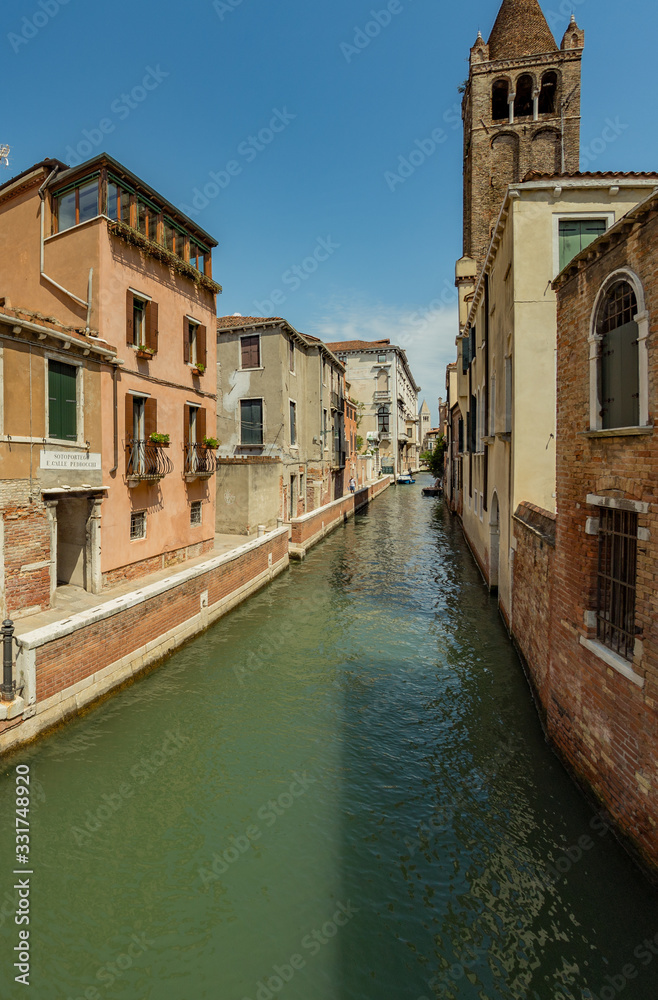 VENICE, ITALY - August 02, 2019: One of the thousands of lovely cozy corners in Venice on a clear sunny day. Historical buildings and canals with moored boats, Vertical frame