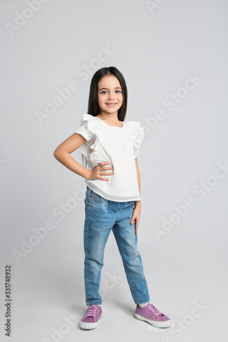Cute little girl posing on light grey background