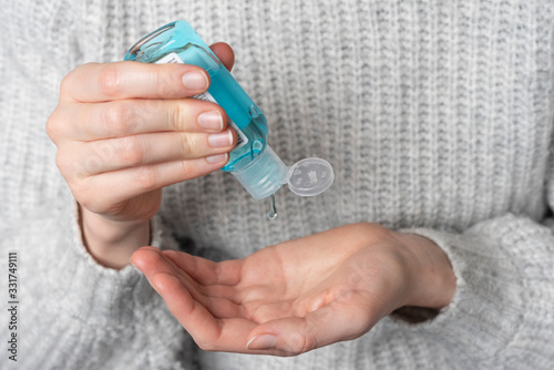 Hand Sanitizer bottle being squeezed into young woman's hand 