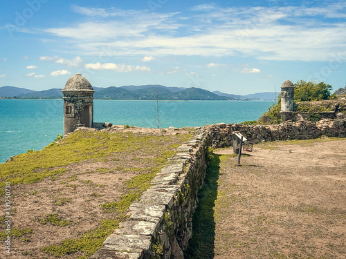 Santa Cruz de Anhatomirim Fortress. view from land to the ocean. on the island there are cannon, fences, viewing platforms and a lighthouse photo