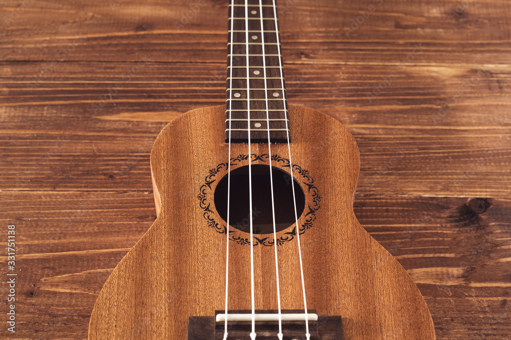 Obraz premium beatiful soprano ukulele with white strings made of zebrawood on aged wood background
