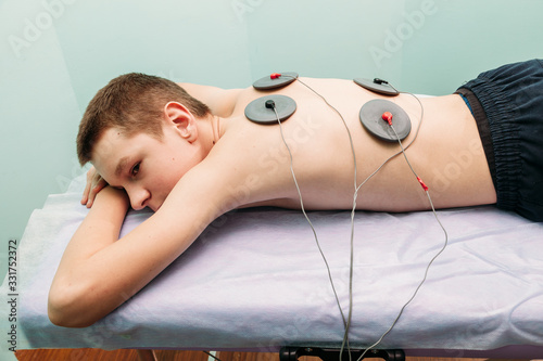 physical therapist positioning electrodes for back muscle treatment young man photo