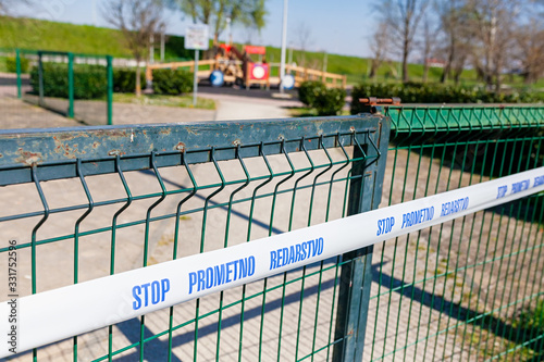 Closed children playground due to corona virus pandemic, with white tape across the gate on a sunny day © Marina P.