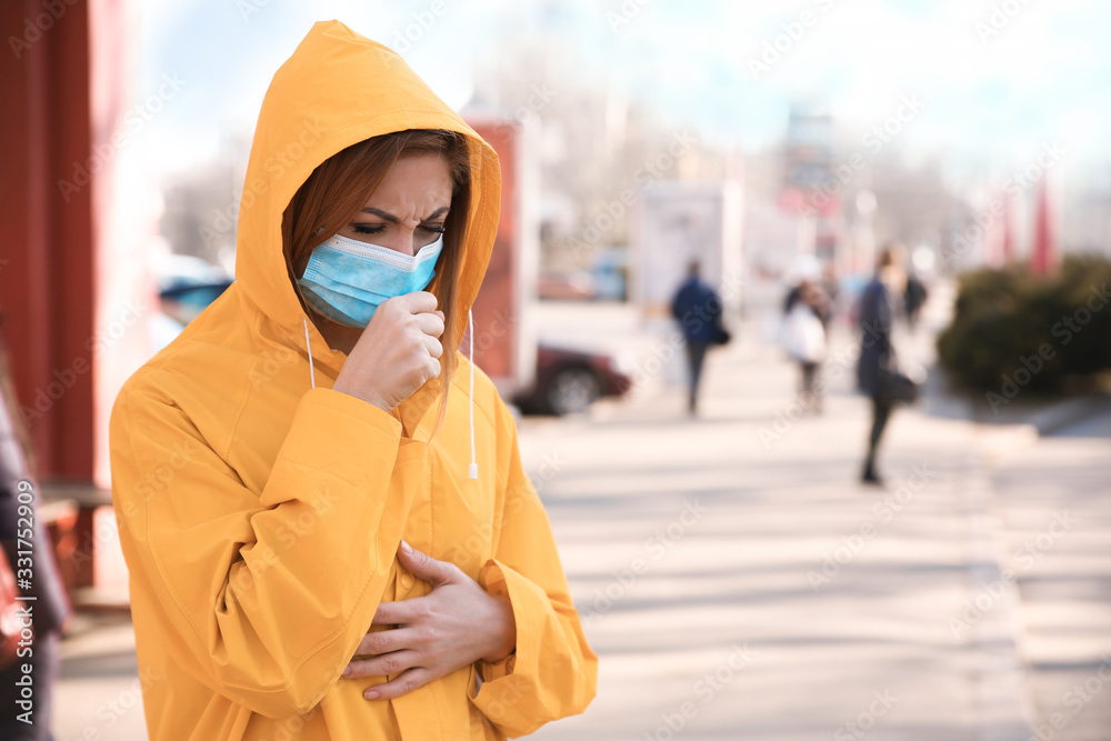 Obraz premium Woman with medical mask coughing on city street. Virus protection