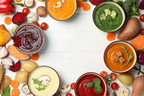Vegetable soups and ingredients on white wooden background, top view