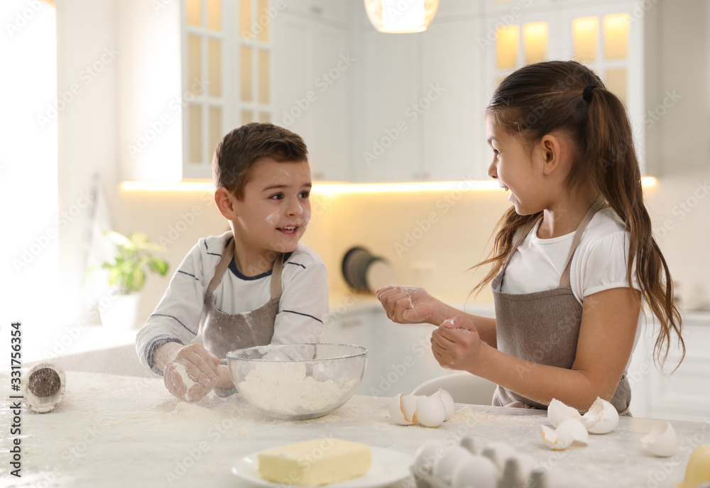 Cute little children cooking dough together in kitchen Cute little children cooking dough together in kitchen