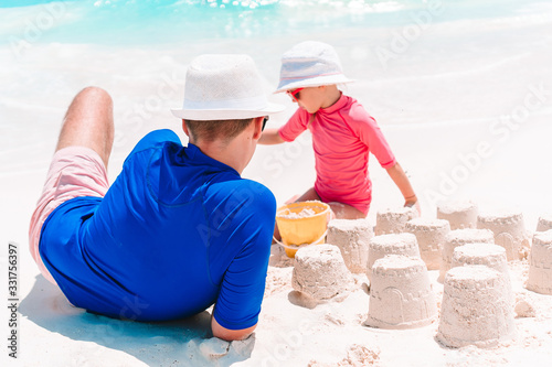 Father and kid making sand castle at tropical beach. Family playing with beach toys