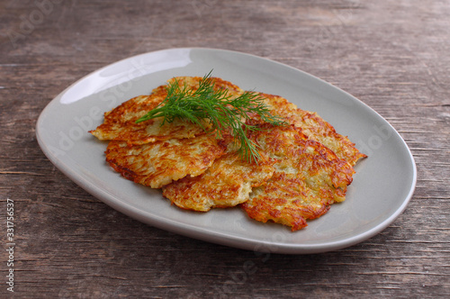 Potato pancakes in a plate decorated with dill on a rustic background