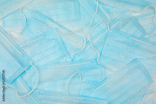 Coronavirus prevention. Close-up of stack typical 3-ply blue surgical medical masks lying on top of each other as background texture. Hygiene corona virus protection concept. Flat lay.