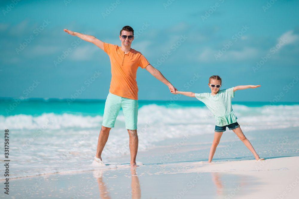 Happy father and his adorable little daughter at tropical beach walking together Happy father and his adorable little daughter at tropical beach walking together