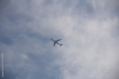 A single airplane has just taken off from Copenhagen airport and is seen from below as it enters the clouds in a bright summer day