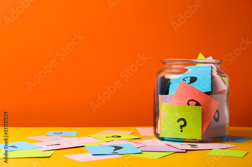Cuadro en lienzo Colorful cards with question marks in glass jar on orange background