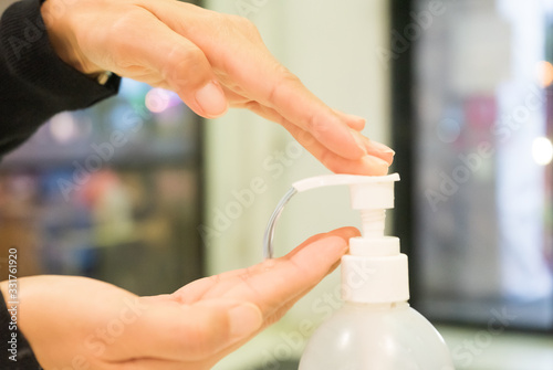 Female using alcohol gel as hand sanitizer at shopping center for prevent the spread of germs and bacteria and avoid infections corona virus. Hygiene concept