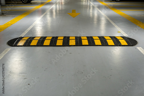 Canvas Print Striped black and yellow speed bump on a road.