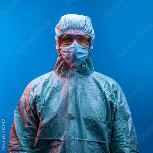 a chemist in a green protective suit , mask and yellow glasses on a blue background