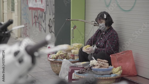 WOMAN PEALS FRUIT IN THE STREET WITH FACE MASK ON