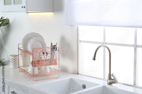 Clean dishes on drying rack in modern kitchen interior