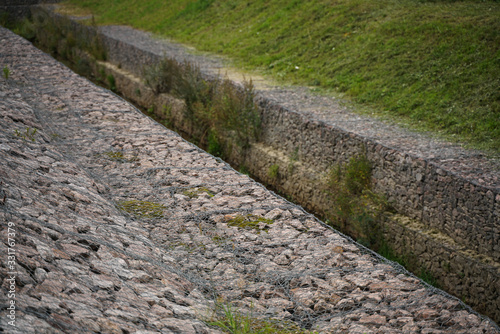 the edge of the city stream, made of stones in an iron grid