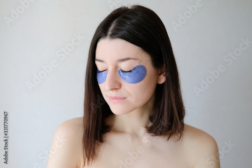 Slika na platnu Beautiful woman with closed eyes applying under eye patches for puffy