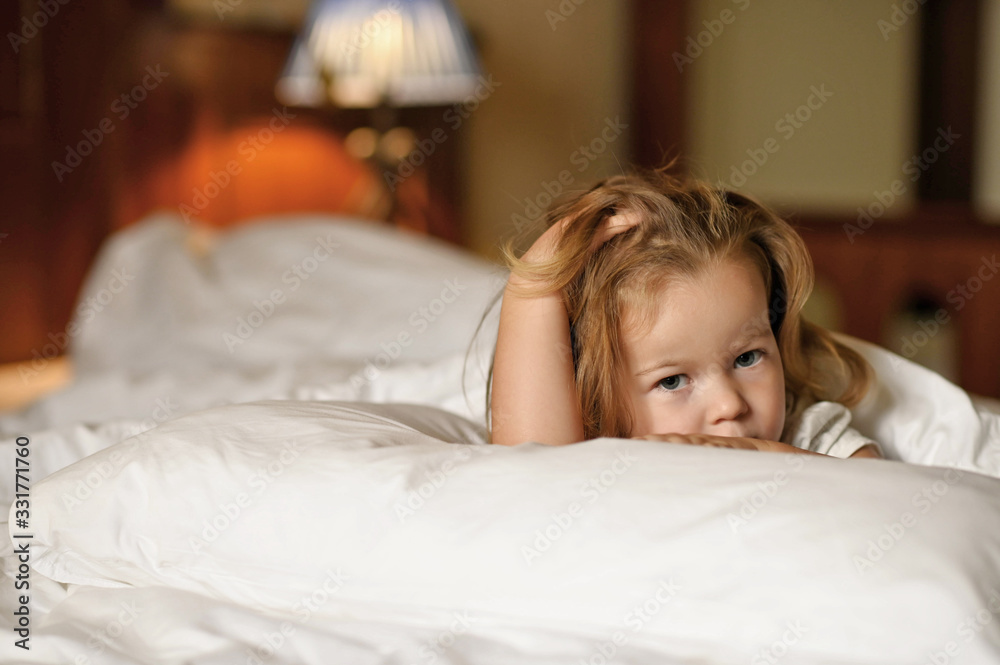 little cute girl 3 years old with dark hair lies in bed with a sad look little cute girl 3 years old with dark hair lies in bed with a sad look