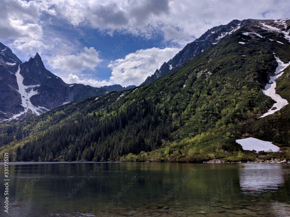 Morskie Oko lake and mountain covered with a green forest Morskie Oko lake and mountain covered with a green forest