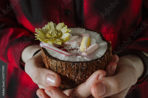 Female hand holding a coconut cocktail with berries and flower