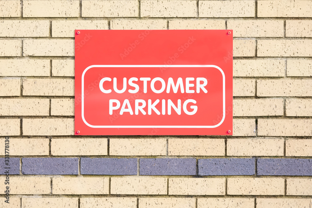 Fototapeta premium Customer parking only sign on brick wall at bank shop car park