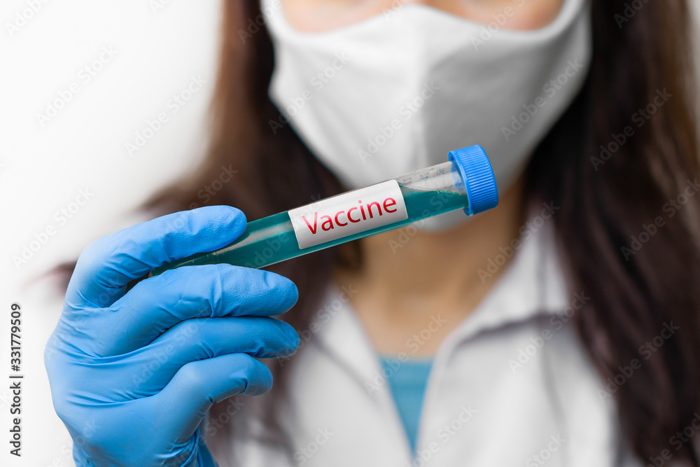 Test tube with vaccine against coronavirus, 2019-nCoV, SARS-nCov, COVID-19 in scientist hand wearing protective mask and blue gloves. Test tube with vaccine against coronavirus, 2019-nCoV, SARS-nCov, COVID-19 in scientist hand wearing protective mask and blue gloves.