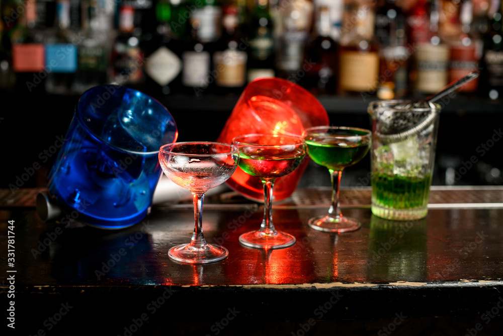 several glasses with green mixture stand on bar counter. Blue and red warning lights inform about quarantine. several glasses with green mixture stand on bar counter. Blue and red warning lights inform about quarantine.