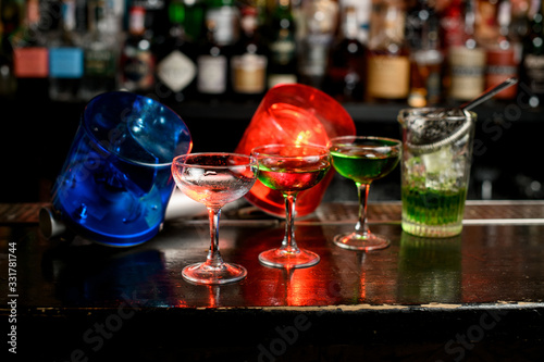 several glasses with green mixture stand on bar counter. Blue and red warning lights inform about quarantine.