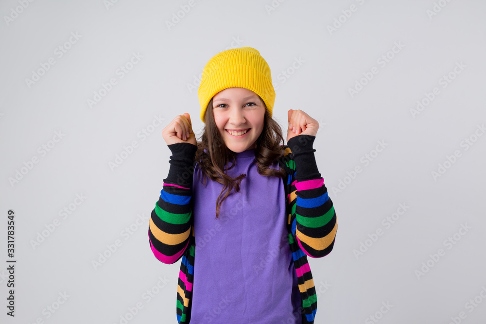 Happy schoolgirl in purple T-shirt and yellow hat on white background