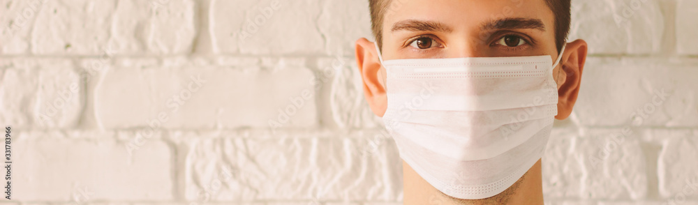 Banner panorama of young professional doctor wearing face mask for protection against coronavirus COVID-19 with copy space. Confident medic surgeon in protective medical face mask. Preventive measures - obrazy, fototapety, plakaty 