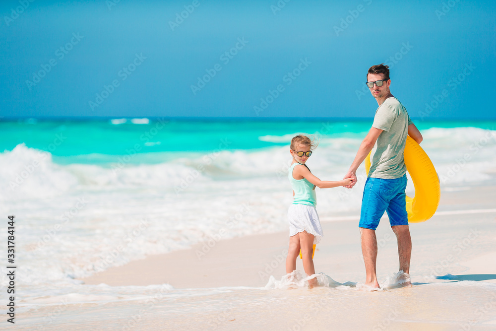 Little girl and happy dad having fun during beach vacation