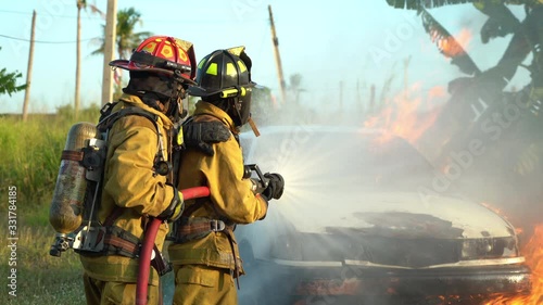 firefighter using spraying water to the fire buring in car accident
