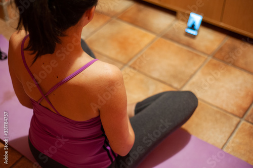 Woman exercising yoga at home with the help of mobile phoneWork from home during an outbreak of the COVID-19 virus. People work at home to prevent virus infection. photo