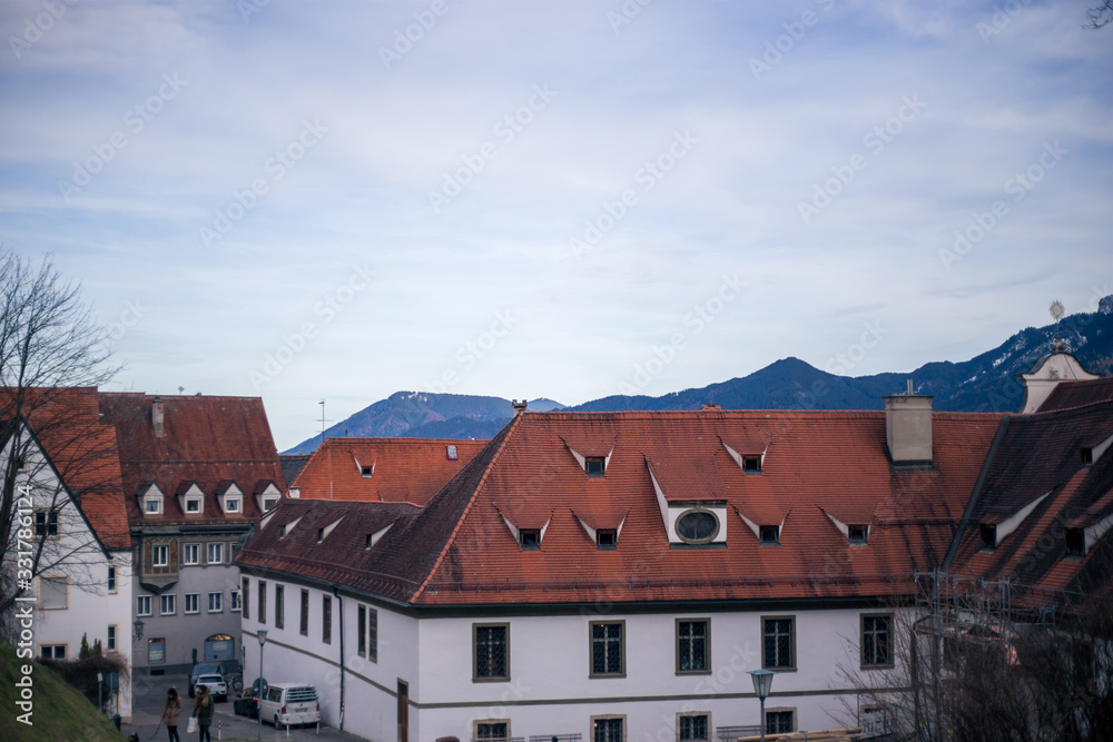 Alpine mountains with snowy peaks. Old european houses. Blue sky with clouds.