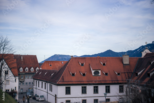 Alpine mountains with snowy peaks. Old european houses. Blue sky with clouds.