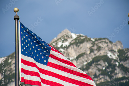 Wawing American flag against mountains of rocks and blue sky