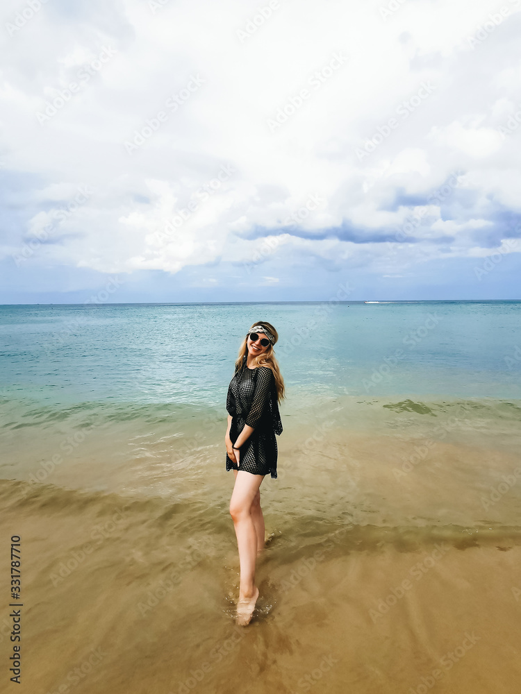 Young attractive girl in hat and glasses on the shore of the blue sea enjoys, Thailand Young attractive girl in hat and glasses on the shore of the blue sea enjoys, Thailand