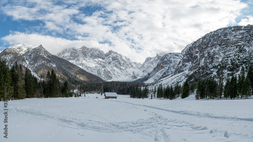 Spectacular winter landscape with freshly fallen snow covering mountain hut surrounded with mountains.